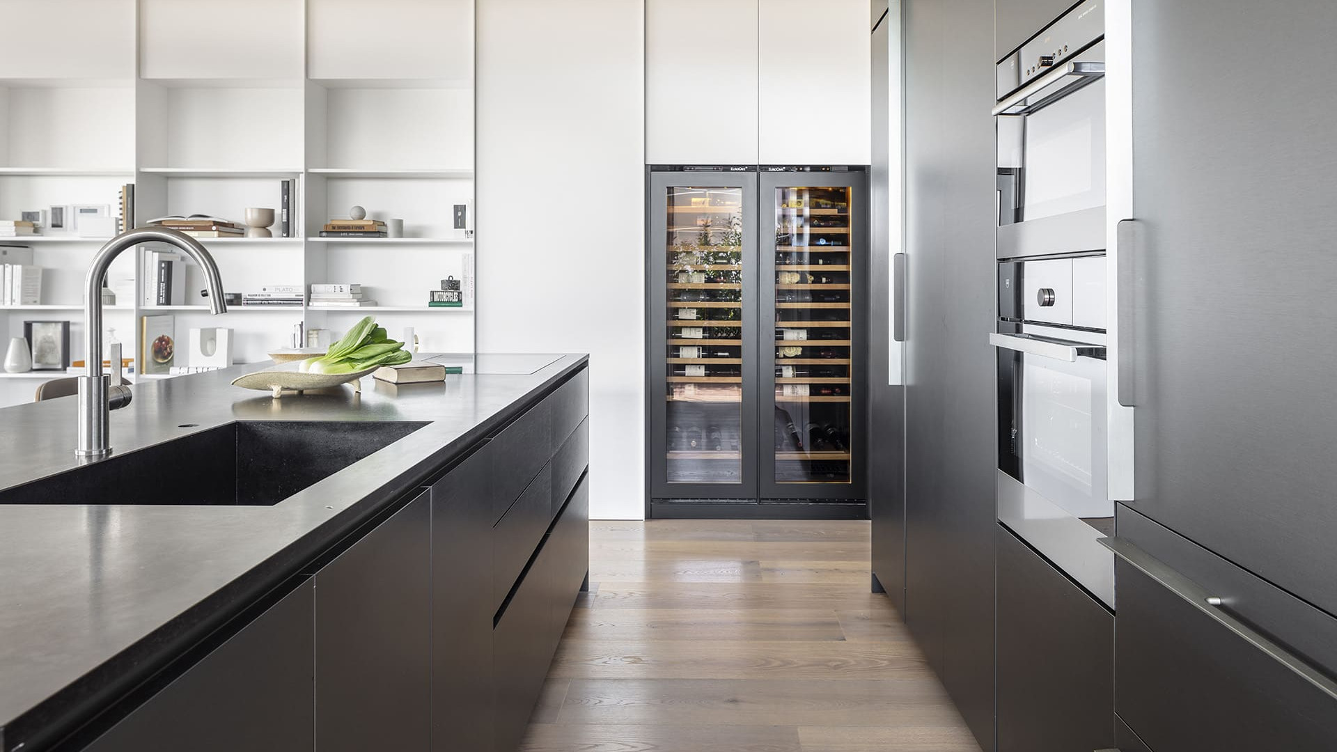Decorative inspiration. Kitchen renovation. Glazed wine cellar integrated into a made-to-measure kitchen unit with an anthracite gray wooden front to underline and highlight it.