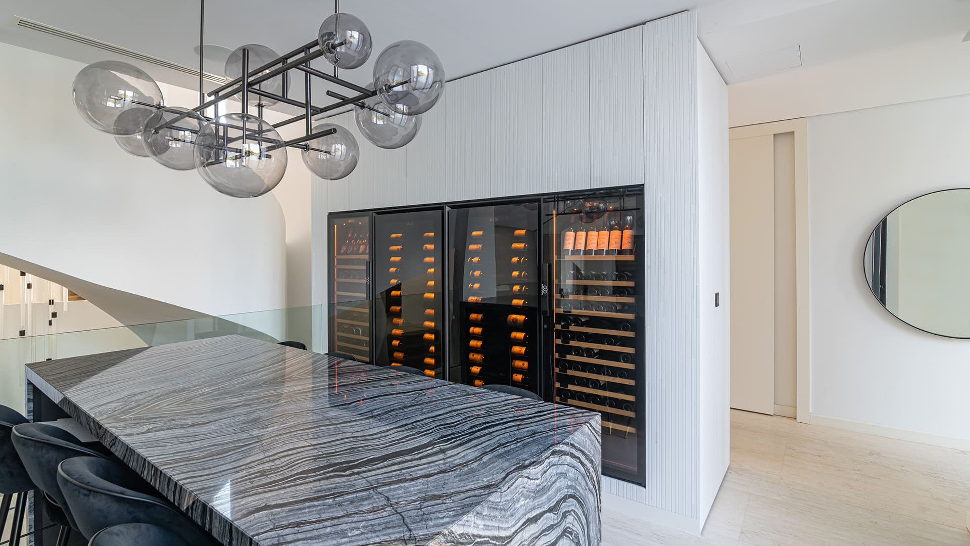 Four wine cabinets built into a custom-made piece of furniture in a residence with prestigious interior architecture. In the foreground a long marble table. - Royale EuroCave