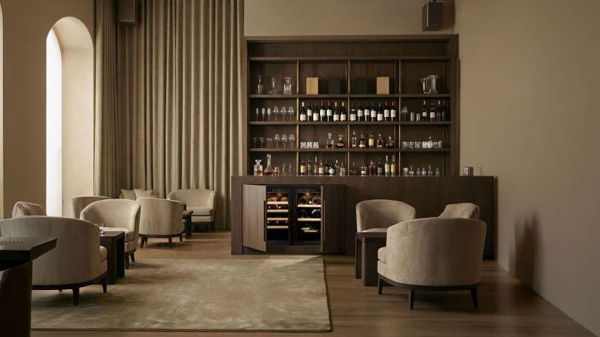 Petites caves à vin EuroCave Compact avec portes techniques pleines ton bois, intégrées côte à côte dans un meuble sur mesure en bois sombre sous un bar contemporain élégant