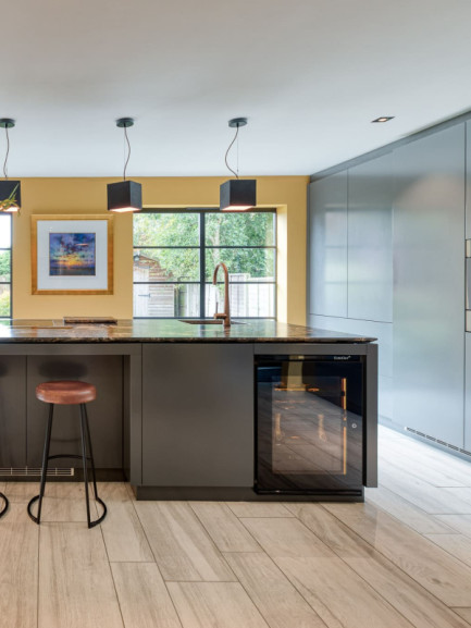 Small wine cooler with glass door built under counter in a contemporary kitchen island, seamlessly integrated into cabinetry, elegant and functional design